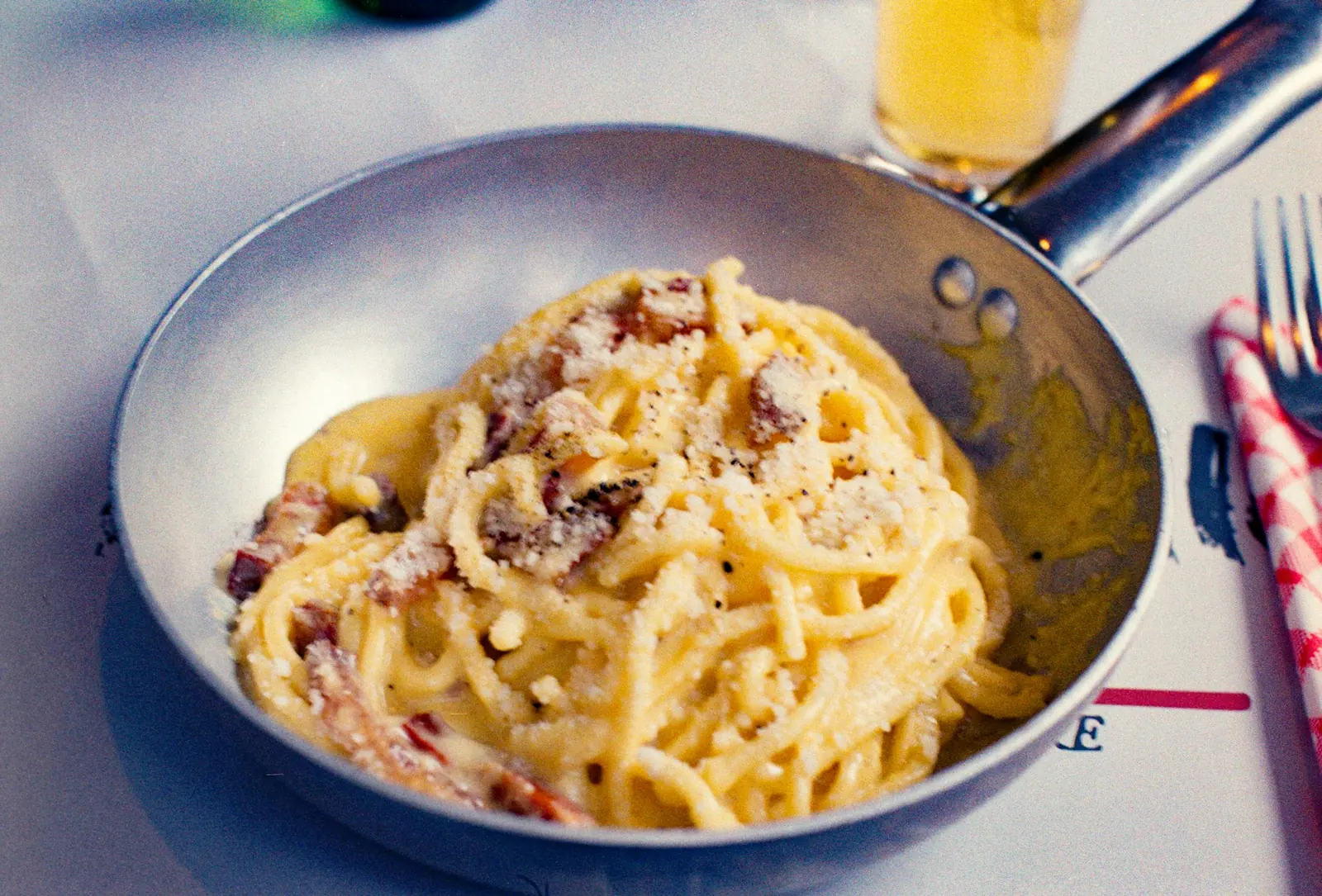 Representative carbonara served in a metal pan with cheese